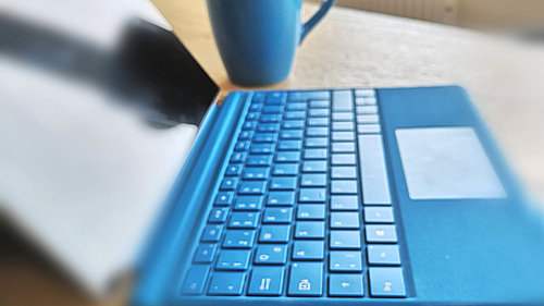 Blauer Laptop mit Tastatur und Tasse